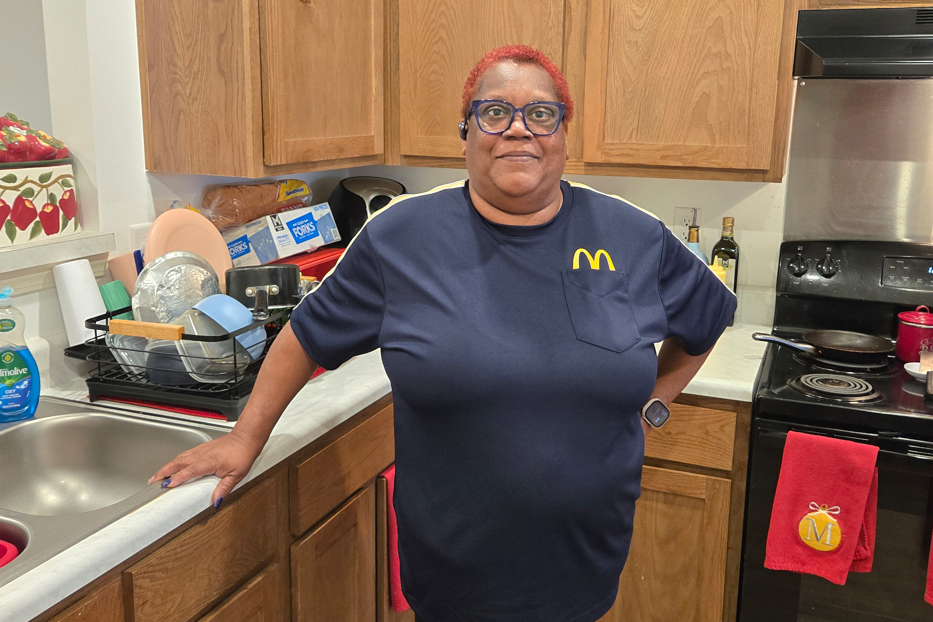 A photo of a woman standing in her kitchen.